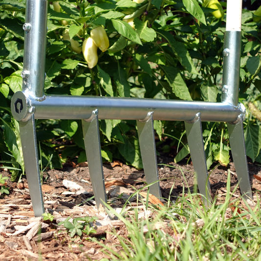 A person using the Green Tools TECH Broadfork for loosening soil in a no-dig market garden.