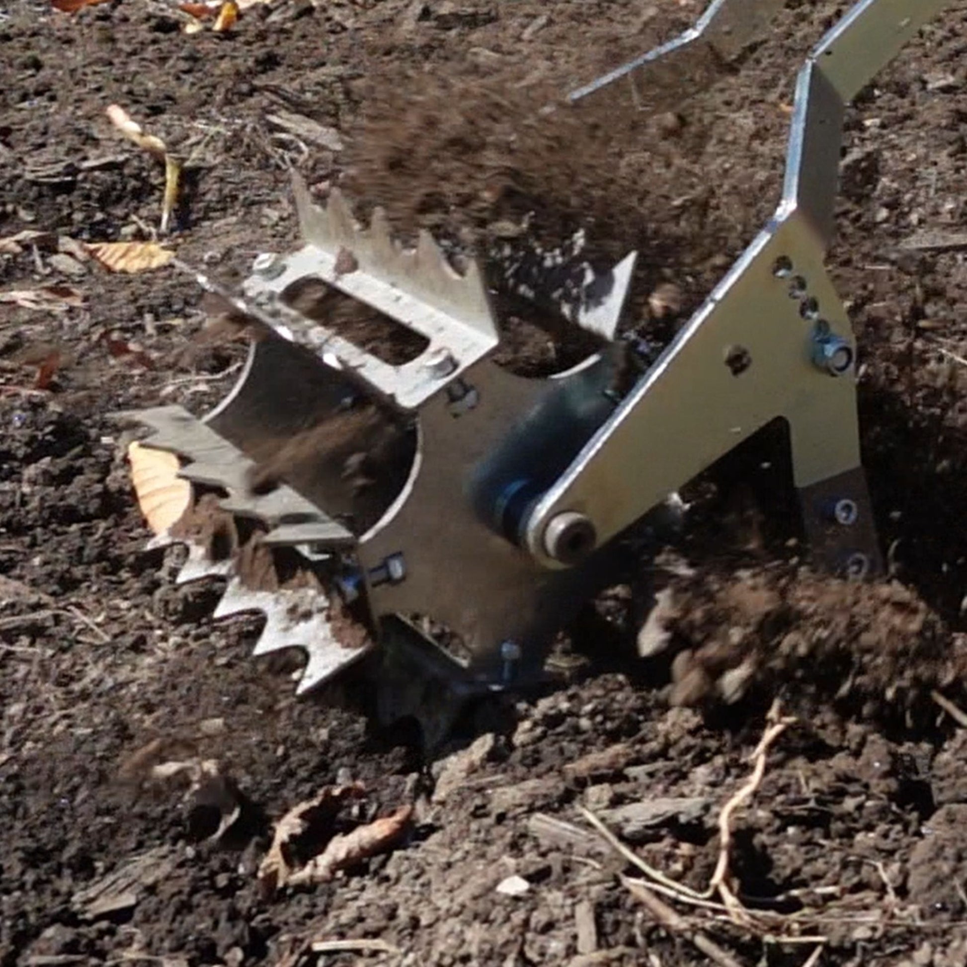 Close-up of Green Tools Tech Roto Hoe rotating drum loosening soil and removing weeds in a no-dig market garden