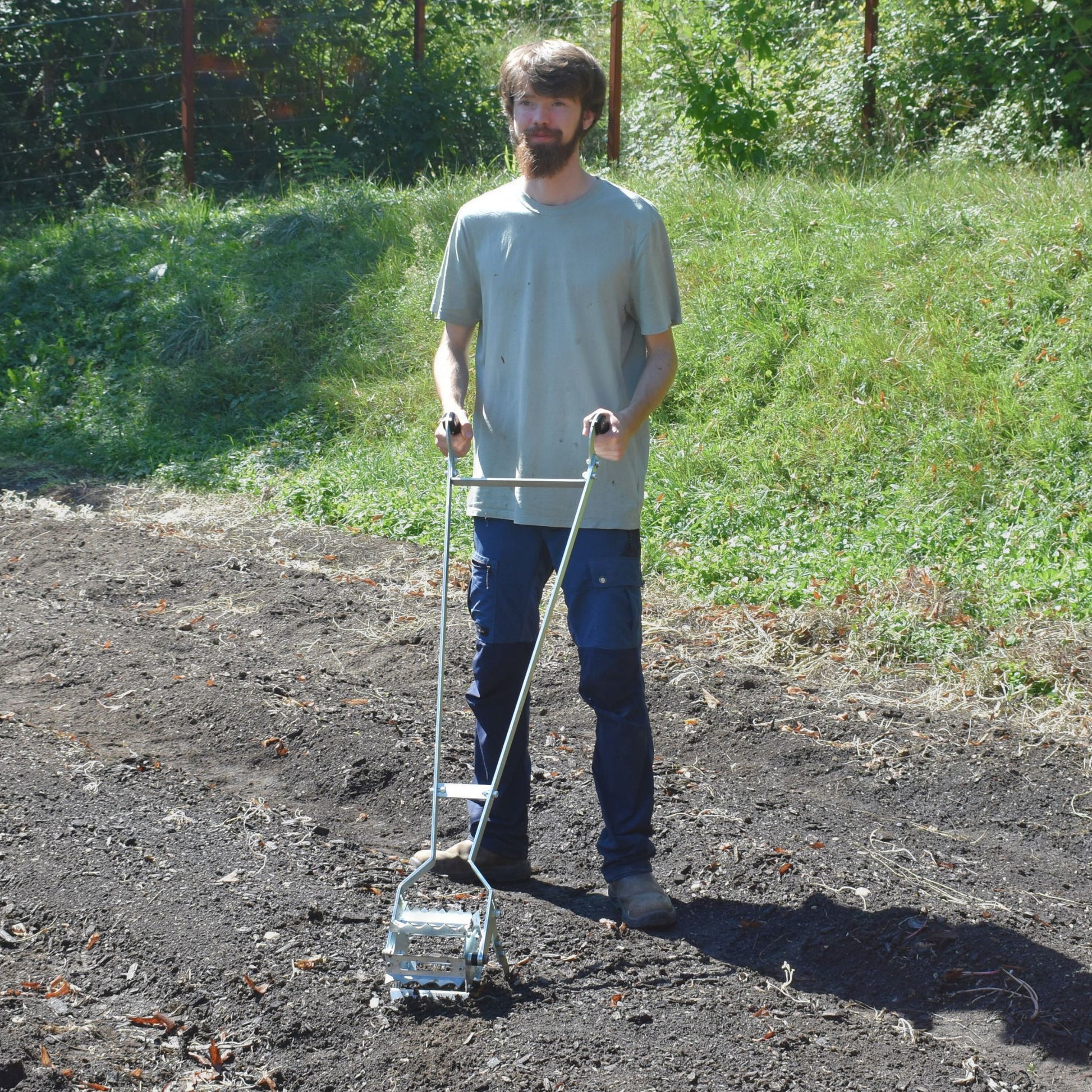 Person using Green Tools Tech Roto Hoe in a no-dig market garden to cultivate and weed raised beds